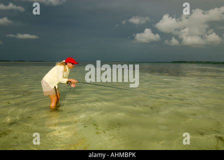 Florida Keys Frau Fischer casting für Bonefish beim Fliegenfischen unter dunklem Himmel auf den Flats auf das Karibische Meer Stockfoto