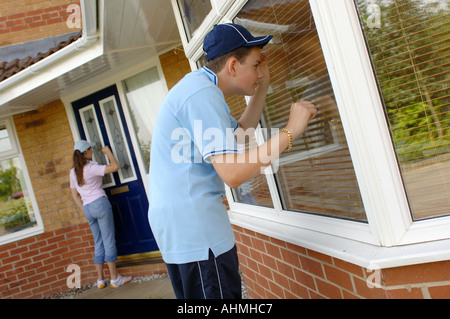 ein Teenager-Mädchen und jungen, verkleidet als Chavs suchen, um in ein Haus einzubrechen Stockfoto