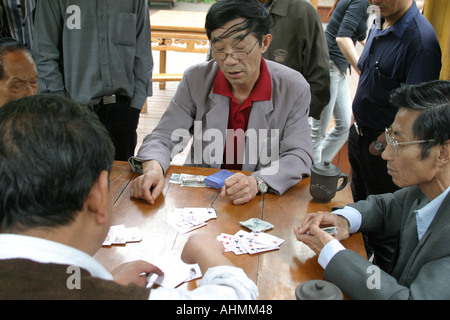 Chinesische Männer sitzen an einem Tisch und Karten spielen an einem Sonntagnachmittag in einem Park in Shanghai Stockfoto