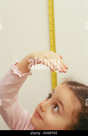 3-jähriges Mädchen ihre Höhe zu messen Stockfoto