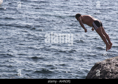 Mittleren Alter Mann, der einen Sprung von Felsen auf Cala della Signora St. Antioco Sardinia Italien Stockfoto