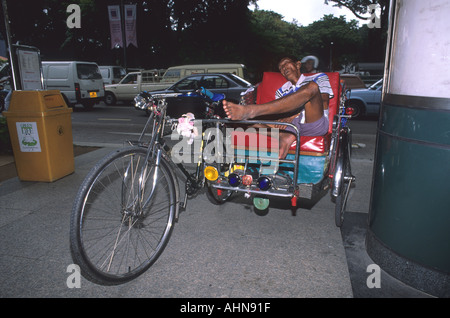 Rikscha-Fahrer schlief auf seinem Dreirad-Rikscha außerhalb der Carlton Hotel Singapore Stockfoto