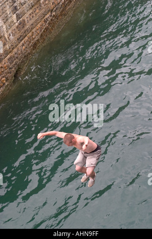 Teenager an Pier ins Meer springen. Brighton, England Stockfoto