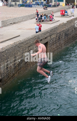Teenager an Pier ins Meer springen. Brighton, England Stockfoto