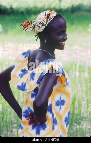 Gambia, Westafrika. Mandinka Frau im traditionellen Batik Kleid im Reisfeld in der Mitte des Gambia-Flusses erreicht. Stockfoto