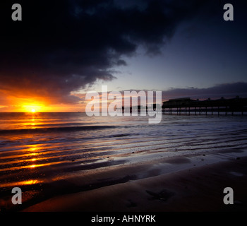 Morgendämmerung auf dem Vorland in Paignton South Devon mit den viktorianischen Pier im Hintergrund und die Sonne an einem bewölkten Himmel Stockfoto