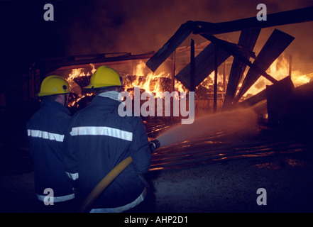 Feuerwehrleute, die mit einem Schlauch Haspel Jet eine Scheune Feuer, Großbritannien UK Stockfoto