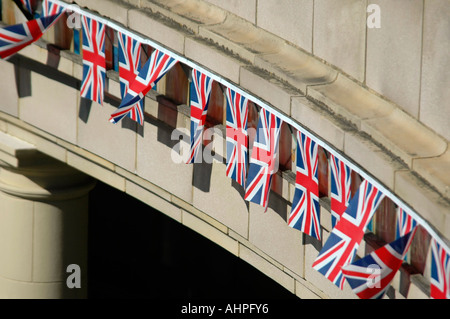 Horizontal in der Nähe einer Reihe von patriotischen Union Jack Bunting Flaggen hängen runden ein Gebäudes nach einer Fete. Stockfoto