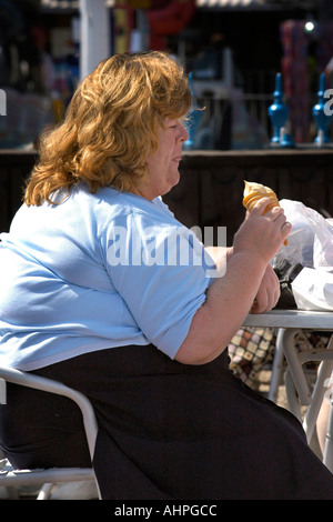 Übergewichtige Erwachsene weibliche sitzen eine doppelte Eis essen. Stockfoto