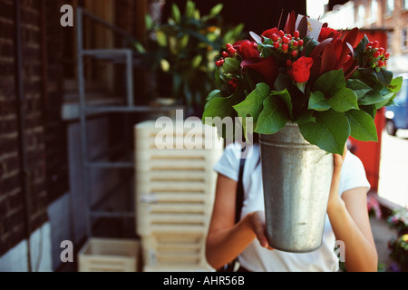 Frau hält einen Eimer mit Blumen Stockfoto