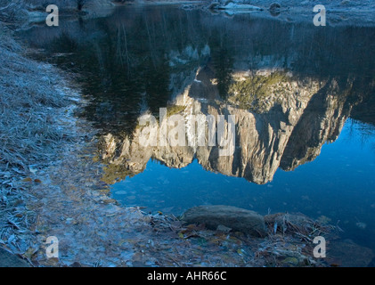 Upper Yosemite Falls im November kurz nach Sonnenaufgang in Merced River mit gefrorenen Bank wider. Stockfoto