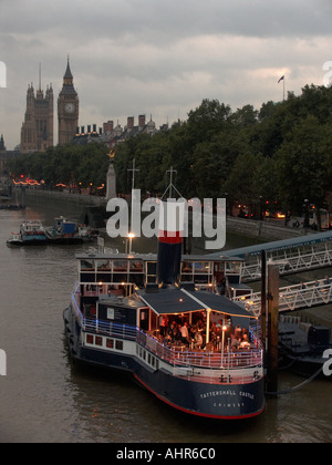 Menschen, die Essen an Bord des Bootes Tattershall Castle vertäut am Victoria Embankment an der Themse mit Big Ben und die Pal Stockfoto