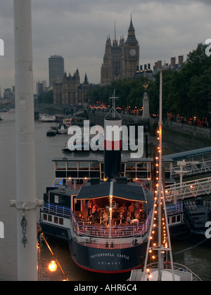 Menschen, die Essen an Bord des Bootes Tattershall Castle vertäut am Victoria Embankment an der Themse mit Big Ben und die Pal Stockfoto