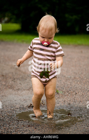 Kind mit einem schmutzigen Blatt stehen in einer Pfütze Stockfoto