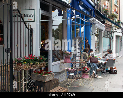 Menschen Sie mit Kaffee und Zeitung lesen am Bürgersteig Tische vor den Geschäften entlang Regents Park Road London England UK Stockfoto