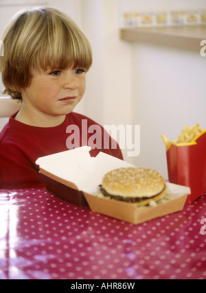 Junge mit Box von Chips und einen Burger - unglücklich Stockfoto