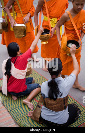 Einheimische Frauen geben Almosen zu Mönchen in Luang Prabang Laos Stockfoto