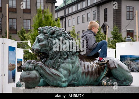Junge spielt auf Löwenstatue am Kungstradgarden in Stockholm Stockfoto