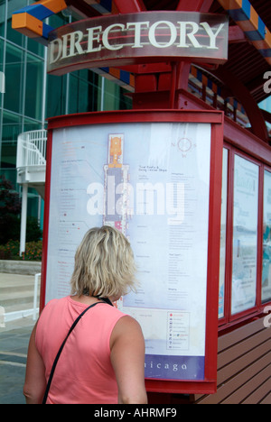 Erwachsene weibliche Blicke auf das Verzeichnis und die Karte zum Navy Pier in Chicago Illinois Stockfoto