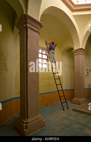 Ein Maler, hoch oben auf einer Leiter in einer Kirche (Mexiko). Peintre de Bâtiment Perché Sur Une Échelle Dans Une Église (Mexiko). Stockfoto