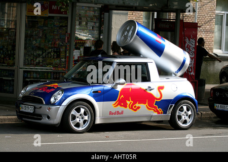 Red Bull Werbeartikel Mini Cooper mit einer riesigen Dose auf dem Dach in Kiew, Ukraine, vor einem 24-Stunden-Geschäft. Stockfoto