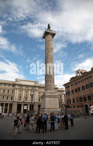 Gruppe von Touristen unter die Säule des Marcus Aurelius gekrönt von Bronze-Statue des Hl. Paulus in Piazza Colonna Rom Latium Italien Stockfoto