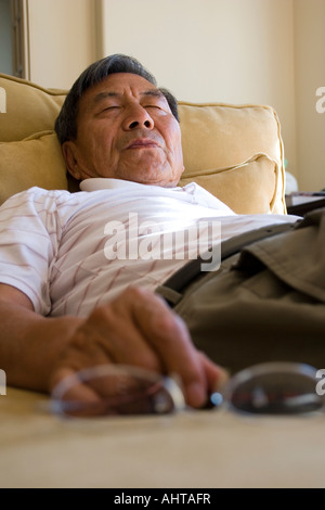 Ältere Mann schlief auf der Couch halten Gläser Stockfoto