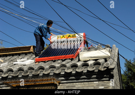 Ein Mann installiert Solarstrom betriebene Warmwasserspeicher Heizung auf Hausdach im Zentrum von Peking, China. 14. Oktober 2007 Stockfoto