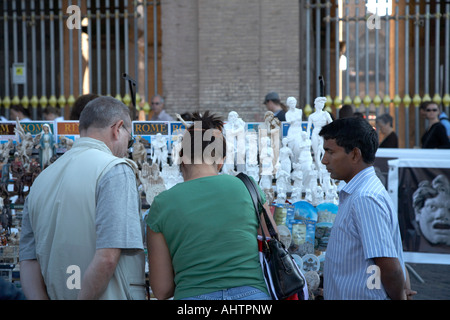 männliche und weibliche Touristen und Straßenhändler untersuchen Artikel auf Souvenir Stall vor der Eingabe Warteschlange außerhalb der Kolosseum-Rom Stockfoto