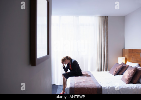 Frau sitzt auf der Bettkante mit Kopf in Händen Stockfoto