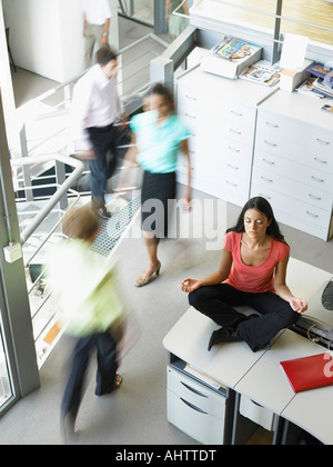 Junge Frau in einer Yogaposition sitzen auf ihrem Schreibtisch Stockfoto