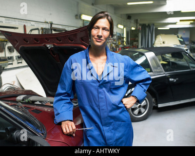 Arbeitnehmerin vor einem offenen Kofferraum in einer Garage. Stockfoto