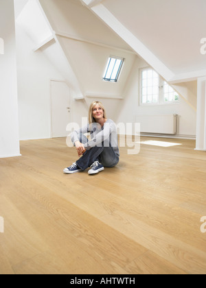 Frau sitzend auf Holzboden von leeren weißen Loft. Stockfoto