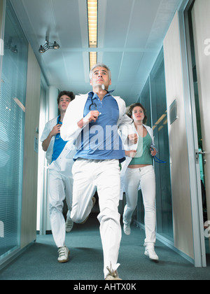 Drei Ärzte laufen in einer Lobby eines Krankenhauses. Stockfoto