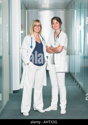 Zwei Ärztinnen, Blick in die Kamera in einer Lobby von einem Krankenhaus Lächeln auf den Lippen. Stockfoto