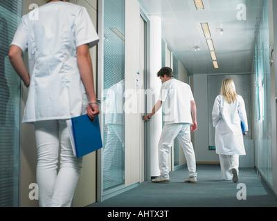 Männlichen Arzt Türöffnung in der Lobby eines Krankenhauses. Zwei Ärztinnen gehen in der Lobby. Stockfoto