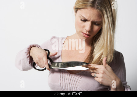 Junge Frau ihr eigenes Haar mit einer großen Schere schneiden. Stockfoto