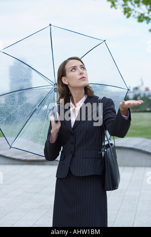 Geschäftsfrau bewaffnet mit Regenschirm prüfen, ob es aufgehört zu regnen. Stockfoto