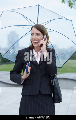 Geschäftsfrau mit Regenschirm auf dem Handy. Stockfoto