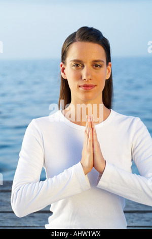 Junge Frau beim Yoga am Dock am Meer. Stockfoto