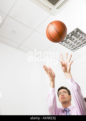 Geschäftsmann in einem Büro werfen einen basketball Stockfoto