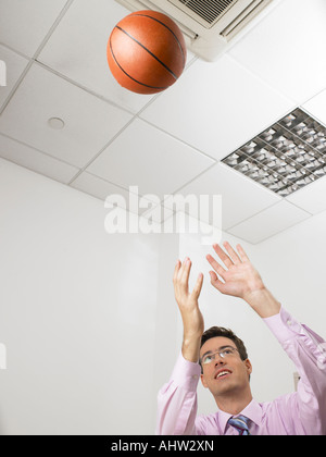 Geschäftsmann in einem Büro werfen einen basketball Stockfoto