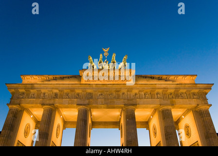 Horizontale Nahaufnahme der Göttin des Sieges-Statue und ihre Pferde auf dem Brandenburger Tor bei Nacht beleuchtet. Stockfoto