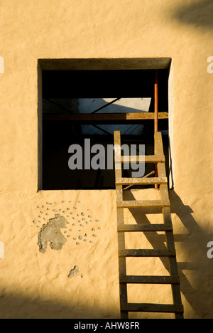 Ein bunter Alter Mexikaner Putz Fenster im Schatten der Dämmerung mit Leiter aufsteigend Stockfoto