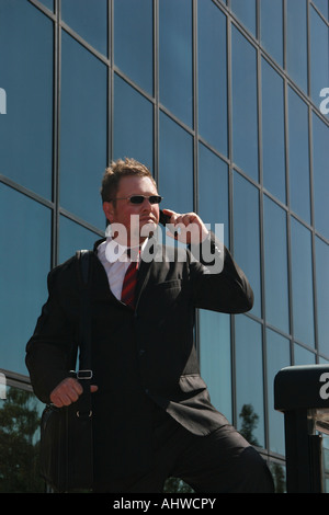 Amerikanischer junger Geschäftsmann, Geschäftsmann, der vor dem Bürogebäude in der Stadtstraße steht und auf dem Handy in den USA Hi-res anruft Stockfoto