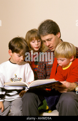 Vater liest eine Geschichte, zwei junge Söhne und Tochter Stockfoto