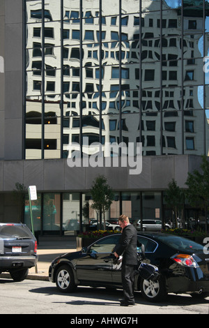 Der Managerin steht neben seinem Auto und ruft das Handy mit einem Laptop an, auf der Straße der Stadt Bilder vertikal in den USA hochauflösende Bilder Stockfoto