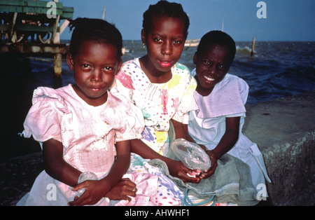Portrait von drei Schwestern sitzen am Meer, Belize City, Belize Stockfoto