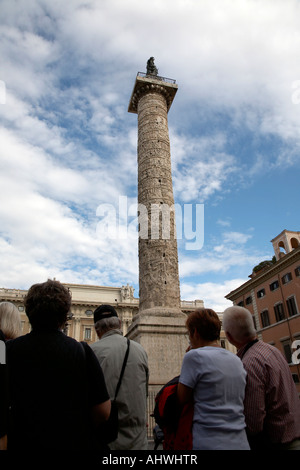 Gruppe von Touristen, die nach oben auf die Säule des Marcus Aurelius gekrönt von Bronze-Statue des Hl. Paulus in Piazza Colonna Rom Latium Stockfoto