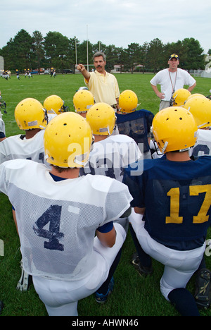 High School Football-Trainer geben aufmunternde Worte für die Spieler vor dem Training Stockfoto